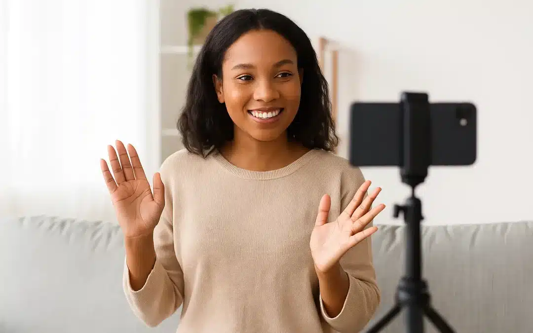Femme souriante en train d’enregistrer un témoignage client avec son smartphone sur trépied dans un salon lumineux.